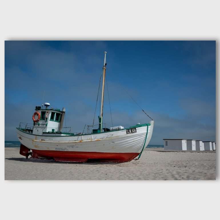 Wanddecoratie At Rest – Vissersboot op Løkken Strand met strandhuisjes op de achtergrond, Denemarken